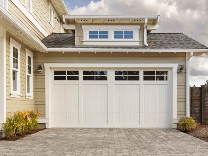 White garage door with a driveway made with brick